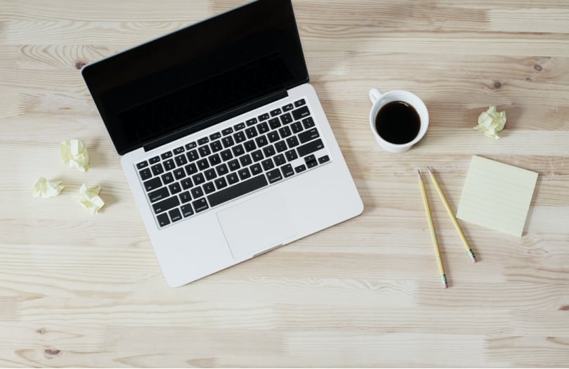 Laptop met koffie en potloden op een tafel